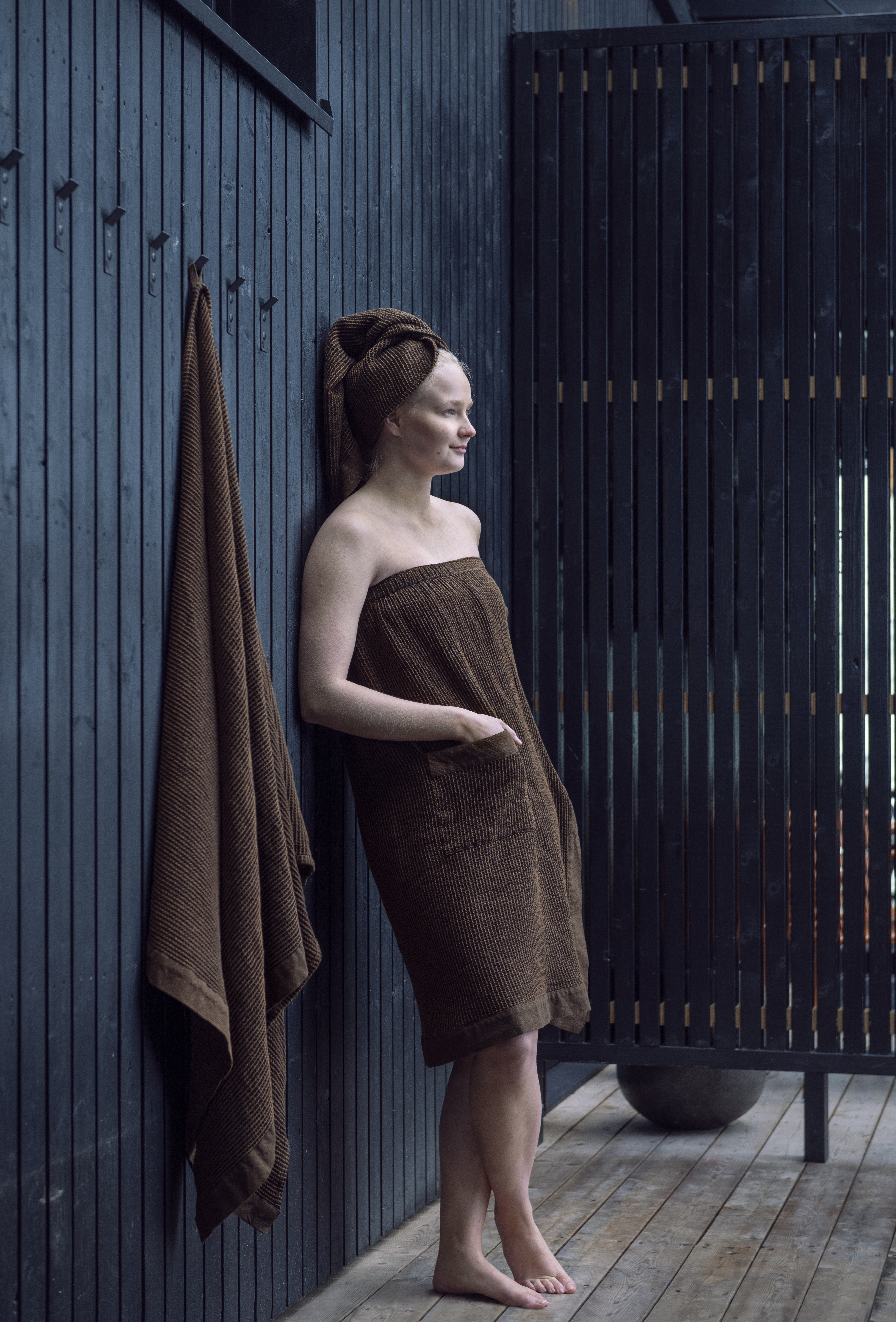 Женщина в саунном фартуке и полотенце для волос.