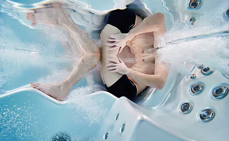 Vyras ilsisi ergonomiškoje USSPA SPA baseino gulimoje vietoje, veikiant hidromasažo purkštukams