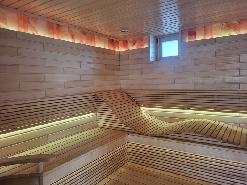Light wood sauna with a wavy bench and LED lighting.