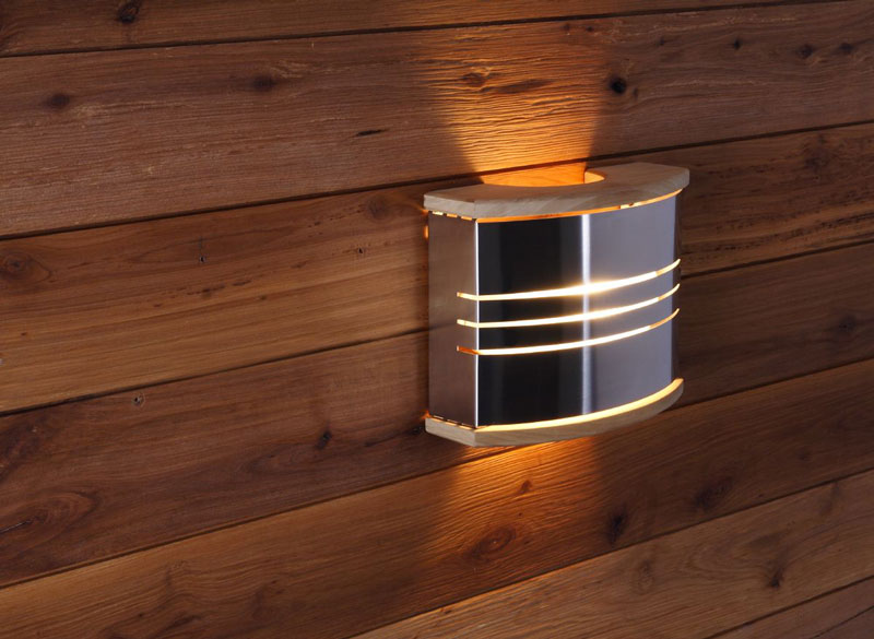 Wall-mounted sauna lamp made of metal and wood on the sauna wall.