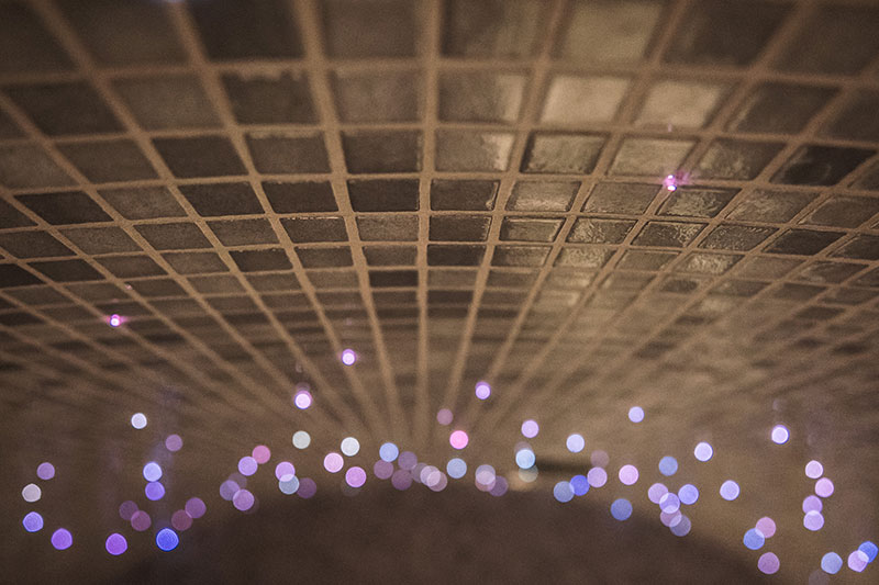 Mozaikinės plytelės su violetiniais atmosferiniais šviesos taškais garinėje pirtyje.
