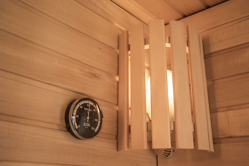 EOS sauna thermometer and wooden lampshade in the corner.
