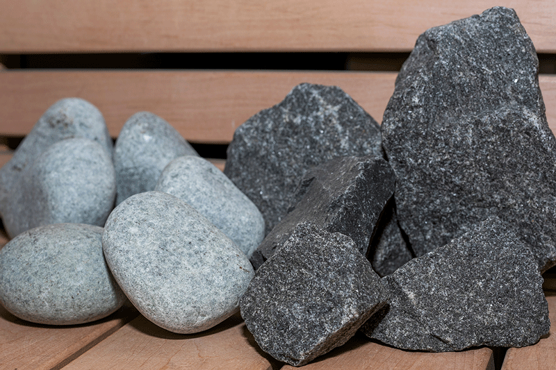 Comparison: rounded river stones and split sauna stones on a bench.
